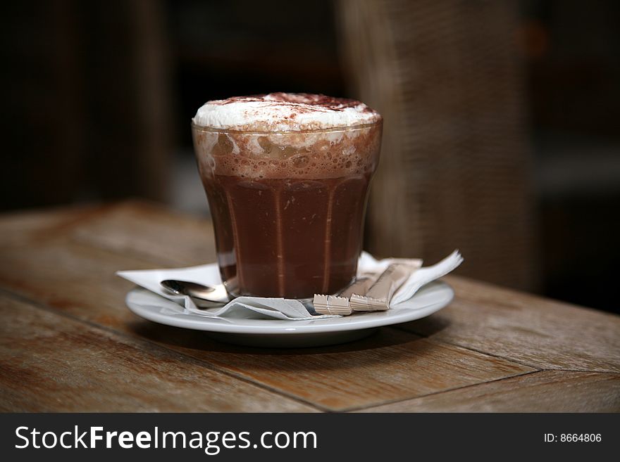 Cappuccino in a glass on a saucer on a table