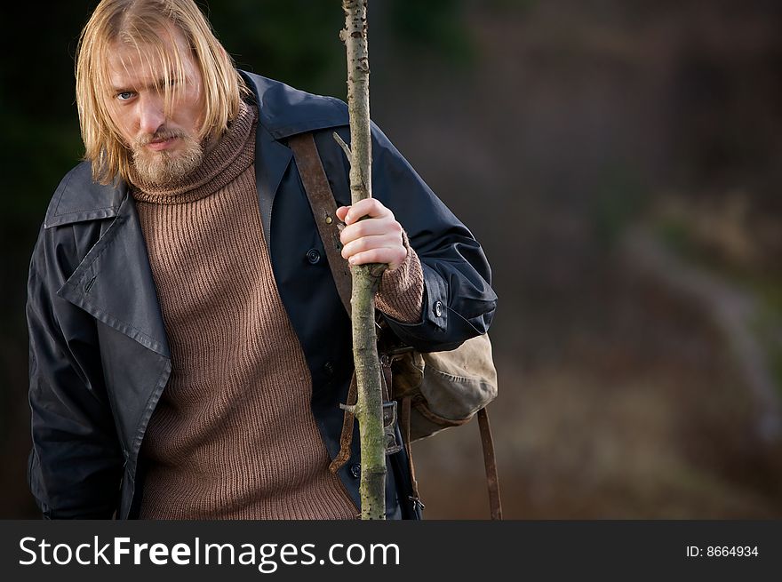 Photo of young man with a stick and a backpack (traveler) in old clothes. Photo of young man with a stick and a backpack (traveler) in old clothes.