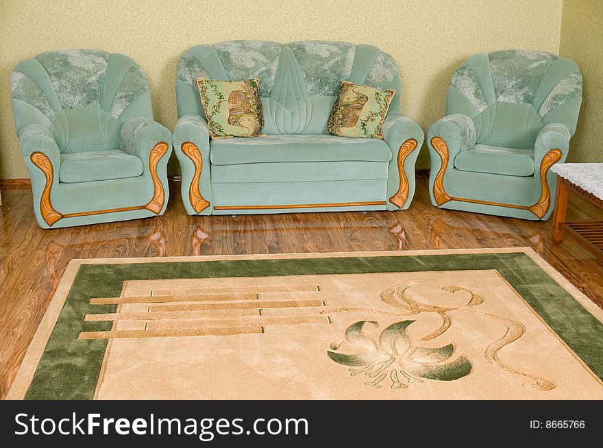 Interior of a drawing room of a room - in a shot the big sofa, two pillows, two armchairs and a beautiful carpet on a floor. Interior of a drawing room of a room - in a shot the big sofa, two pillows, two armchairs and a beautiful carpet on a floor.