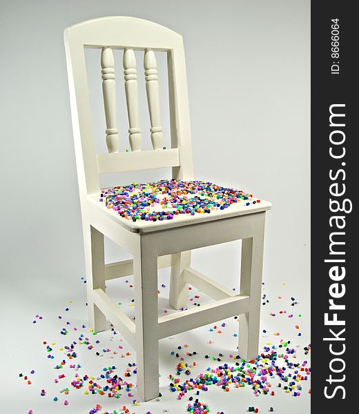 White wooden chair with multi coloured beads
