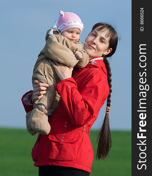 Little baby with mom on green grass and blue sky background