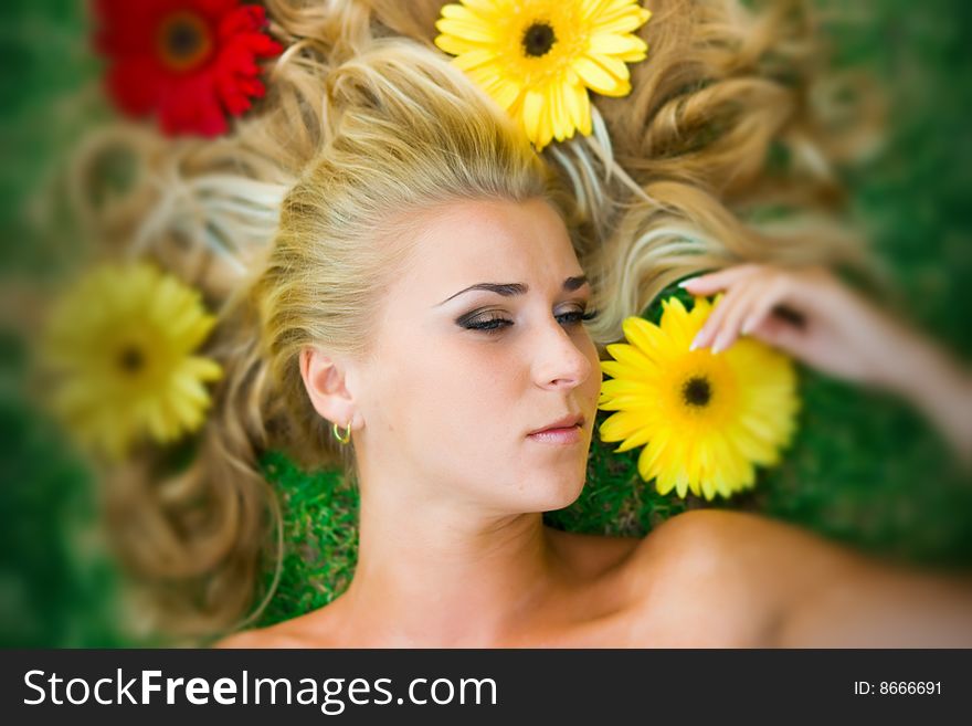 Beautiful blonde girl in lying on the grass with her hair in flowers. Beautiful blonde girl in lying on the grass with her hair in flowers