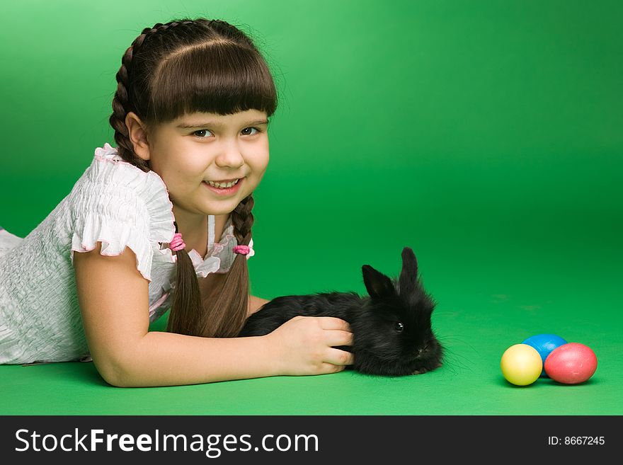Girl lies near to a rabbit and Easter eggs