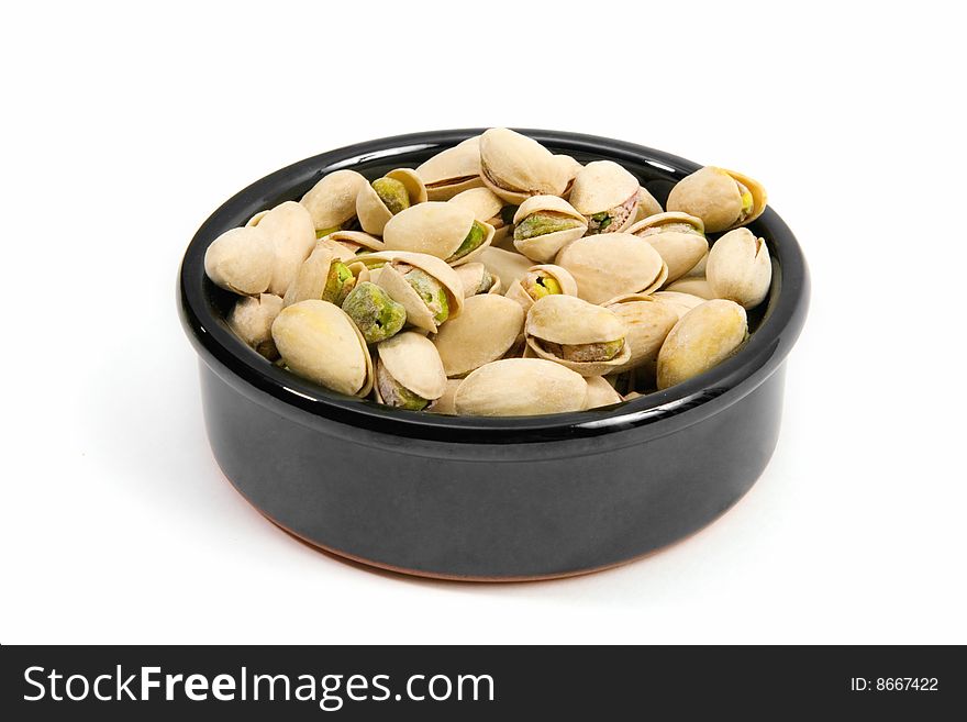 Pistachios in a ceramic bowl isolated on a white background.