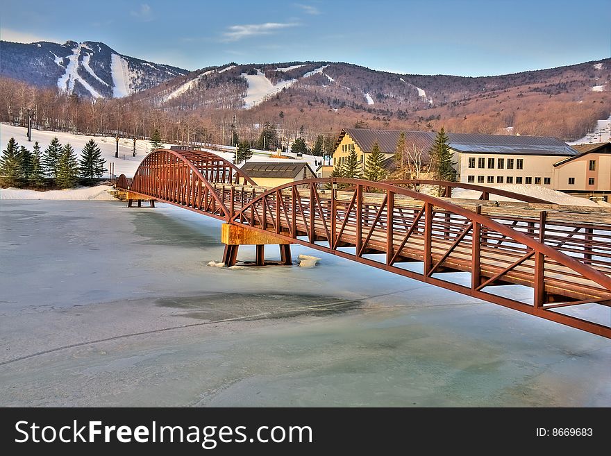 View of a framed bridge leading to a ski resort in high dynamic range.