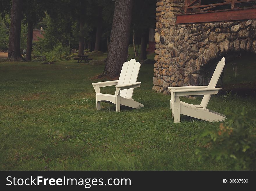 Two White Wooden Lawn Chairs In Grass By Home