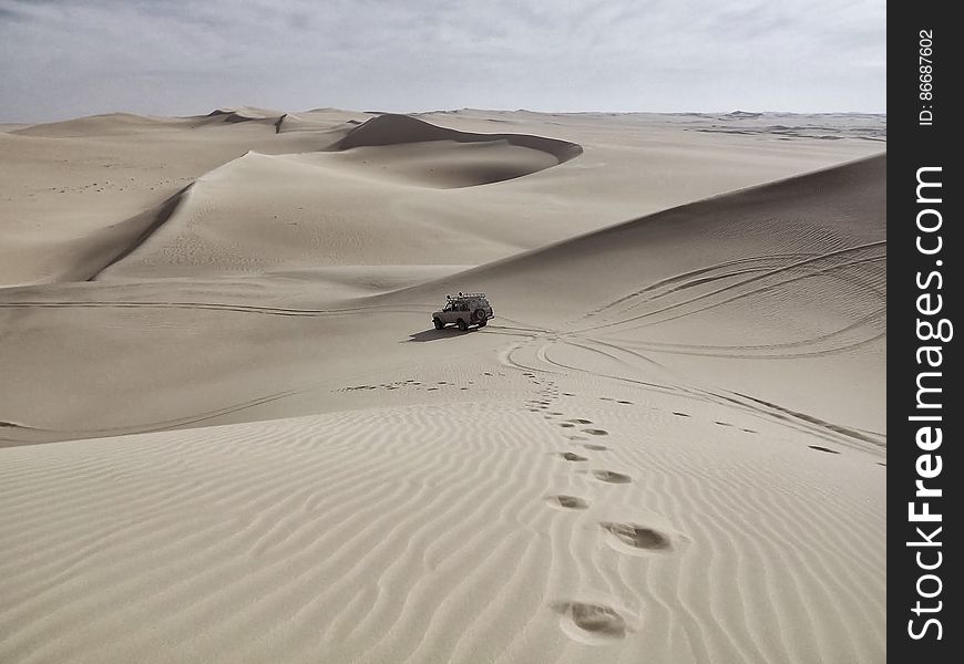 Automobile And Tire Tracks In A White Desert With Sand Dunes