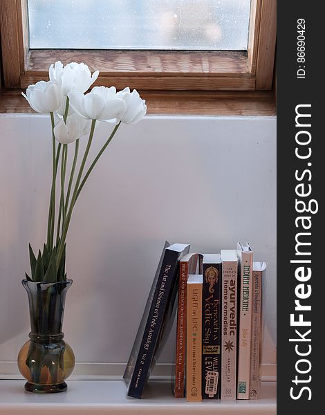 White tulips in a vase on a windowsill, which also has books on ayurveda and astrology standing on it. White tulips in a vase on a windowsill, which also has books on ayurveda and astrology standing on it.