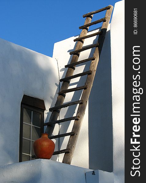 white adobe house with ladder