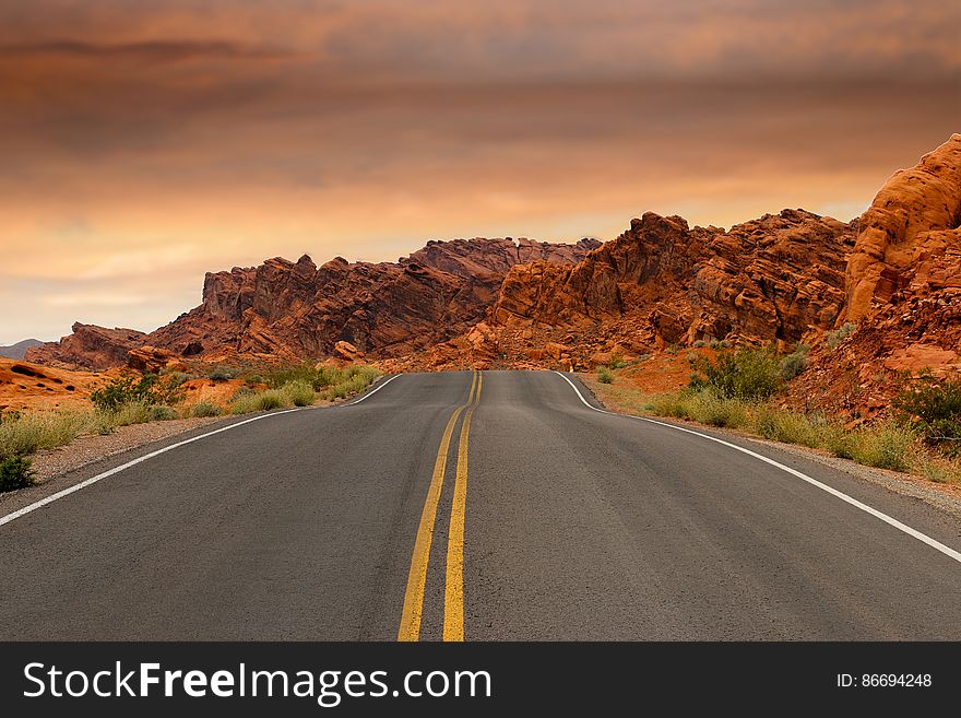 Gray Concrete Road Beside Brown Mountain During Golden Hour