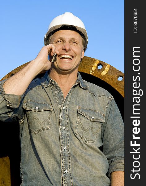 A portrait of a happy smiling construction worker leaning against large metal pipes. A portrait of a happy smiling construction worker leaning against large metal pipes.