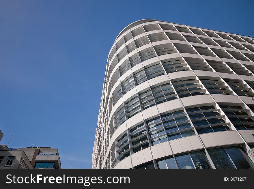 Photograph of a round corner of a smart looking building, shot against a clear blue sky. Photograph of a round corner of a smart looking building, shot against a clear blue sky.