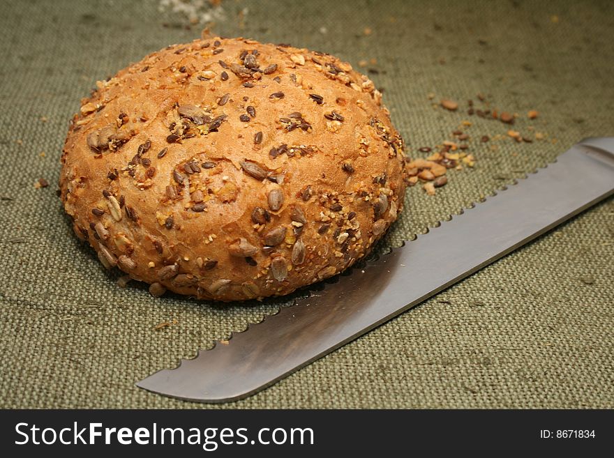 Close-up A whole-grain roll  with bread  knife. Close-up A whole-grain roll  with bread  knife