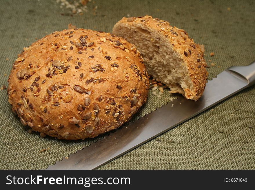 Close-up A whole-grain roll  with bread  knife. Close-up A whole-grain roll  with bread  knife