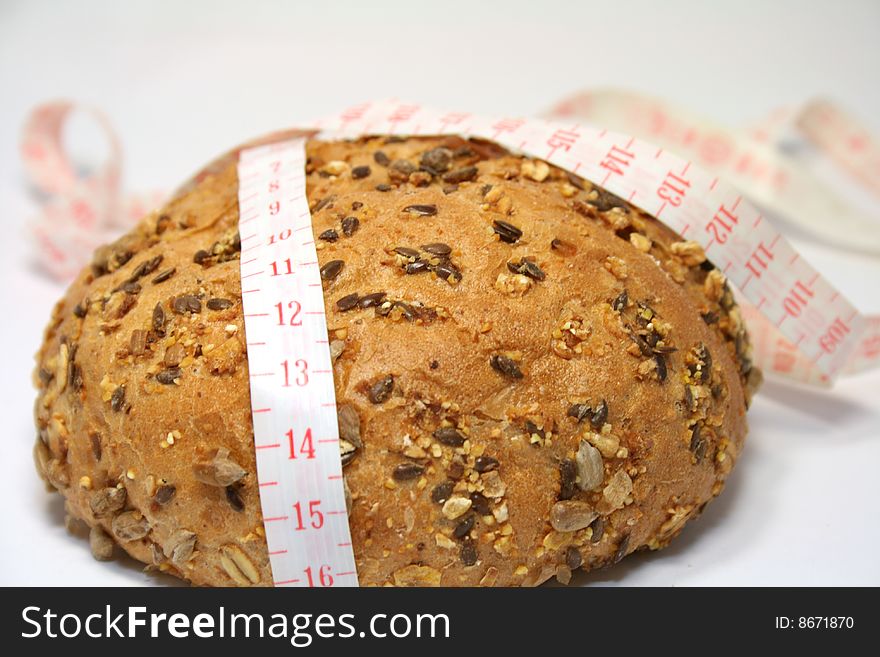 A whole-grain roll with a measuring tape. A whole-grain roll with a measuring tape.