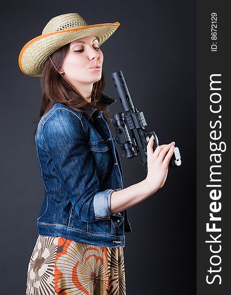 Girl in a cowboy's hat with the big pistol against a dark background. Girl in a cowboy's hat with the big pistol against a dark background