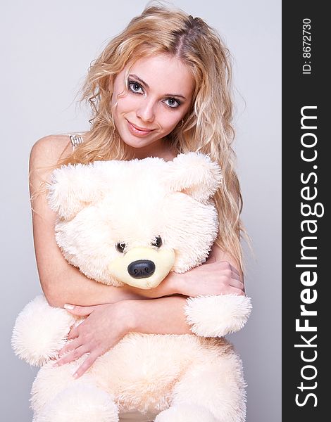 Beautiful girl with a teddy bear on a gray background