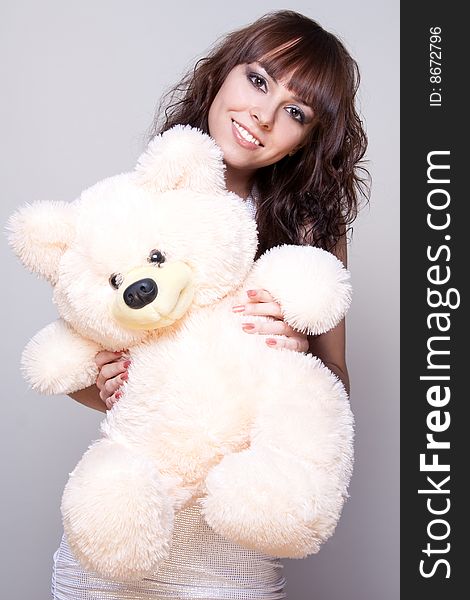 Beautiful girl with a teddy bear on a gray background