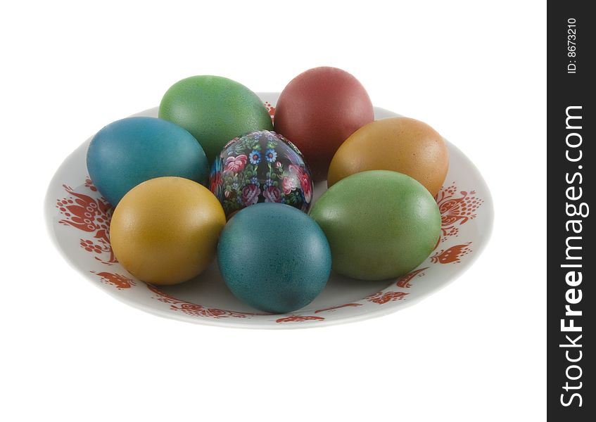 The easter decorated eggs lying in white porcelain plate with a red ornament