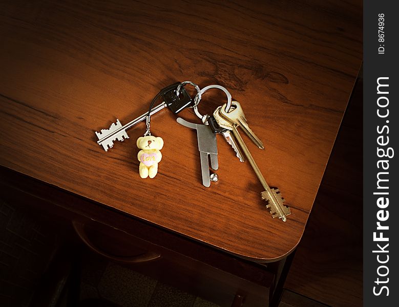 A bunch of keys with a soccer player and a teddy bear trinkets. A bunch of keys with a soccer player and a teddy bear trinkets