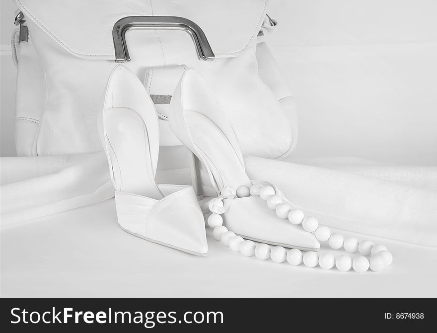 A picture of a white bag, shoes and beads on white background. A picture of a white bag, shoes and beads on white background