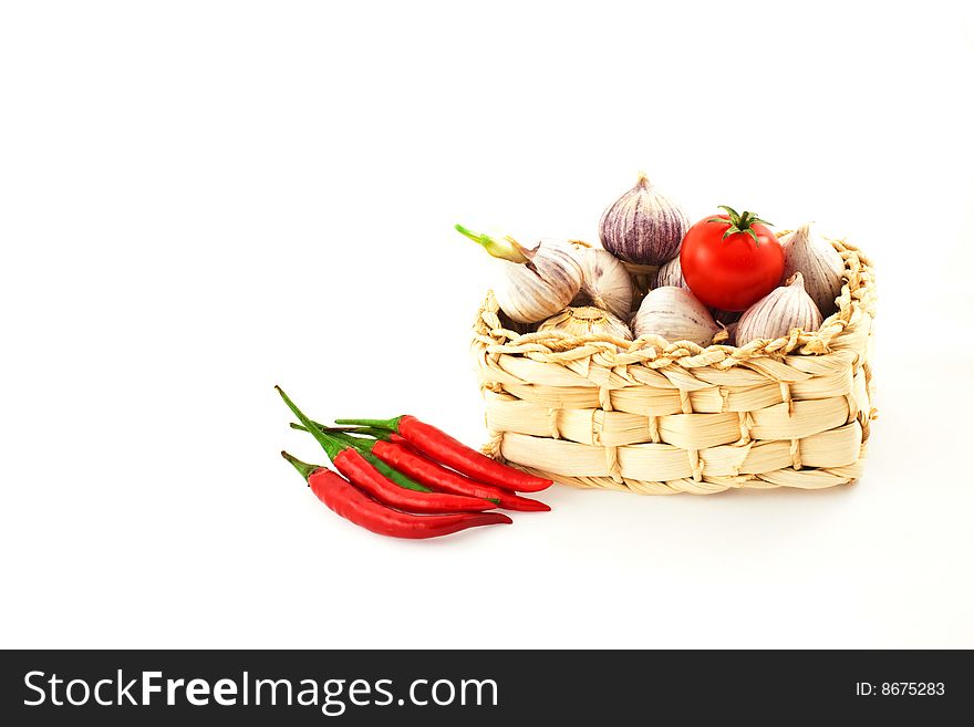 Tomatoes, pepper and garlic in a basket on a white background