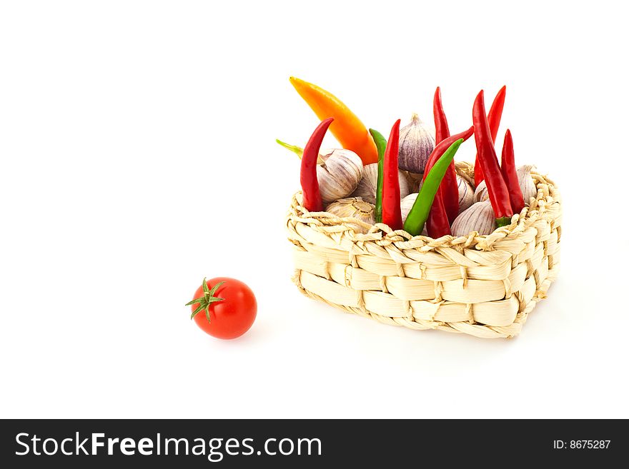 Tomato, pepper and garlic in a basket on a white background