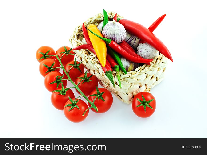 Bunch of tomatoes, pepper and garlic in a basket on a white background