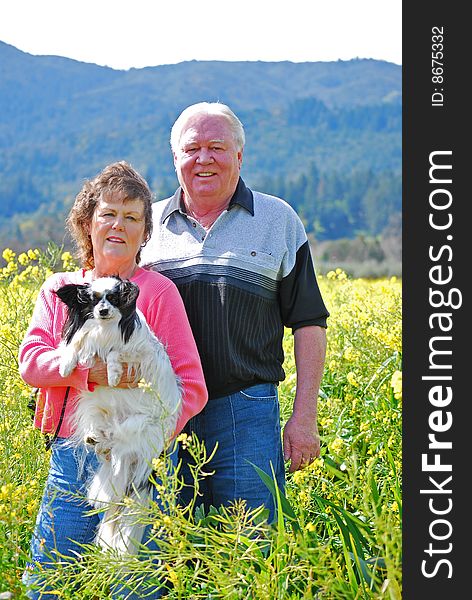 Happy couple posing in a mustard field with their dog. Happy couple posing in a mustard field with their dog.