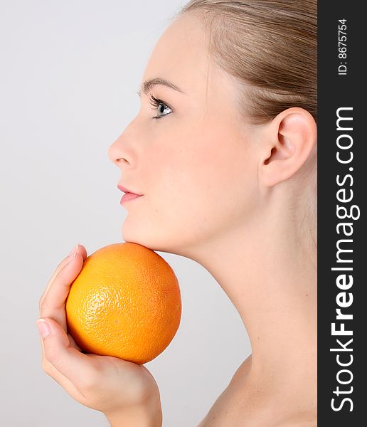 Beautiful young model holding an orange under her chin. Beautiful young model holding an orange under her chin