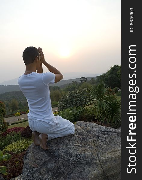 A man welcoming the sun with prayer and yoga movements on a mountain