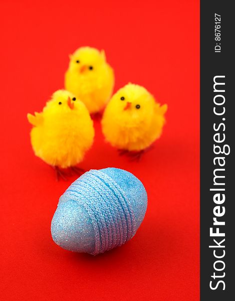 Blue Easter egg and three chicks isolated on red. Shallow depth of field. Focus on egg. Blue Easter egg and three chicks isolated on red. Shallow depth of field. Focus on egg.