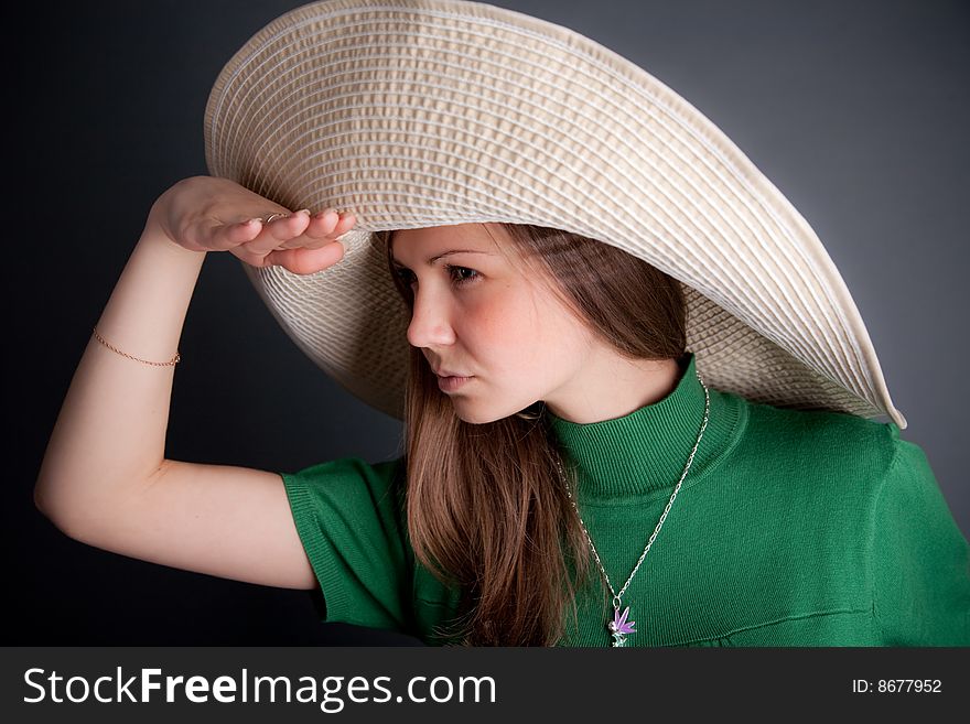 Funny young cutey in a green dress with a big straw hat is looking to the horizont. Funny young cutey in a green dress with a big straw hat is looking to the horizont