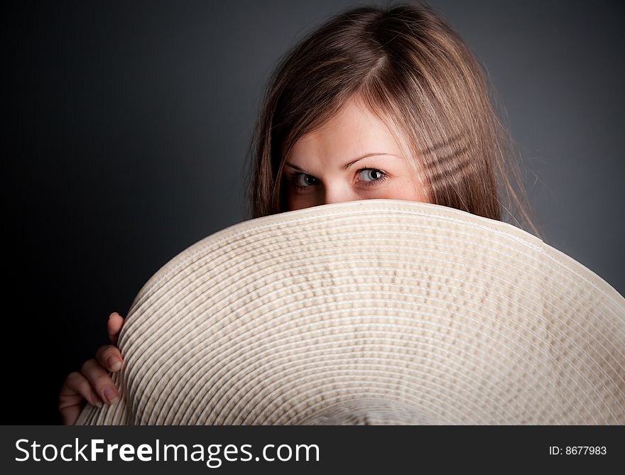 Pretty young girl is hiding behind the hat