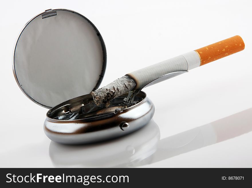 Ashtray with cigarette on white background