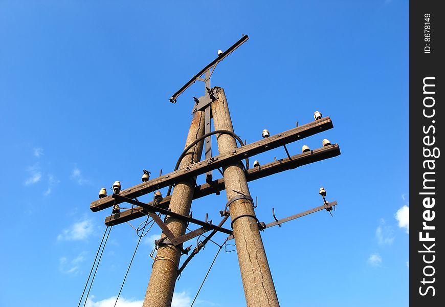 Old collapsing column of an electric main on background of blue sky. Old collapsing column of an electric main on background of blue sky