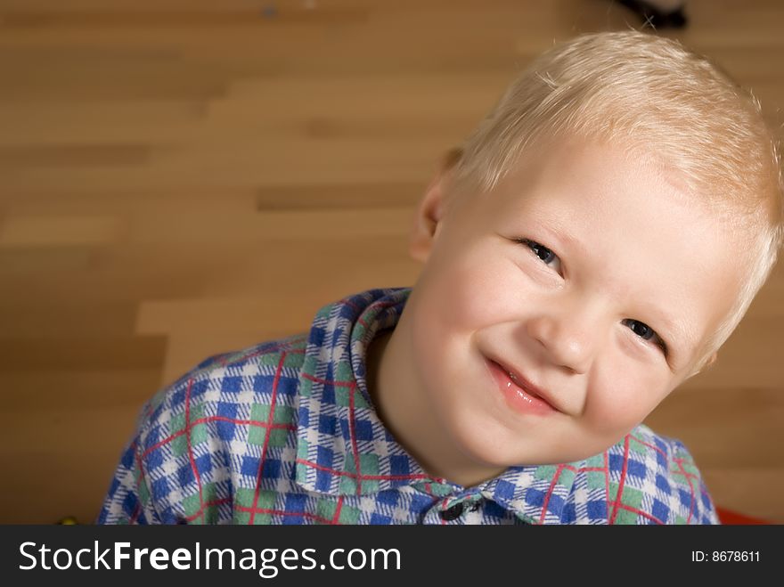 There is a little boy sitting on the floor and smile. There is a little boy sitting on the floor and smile