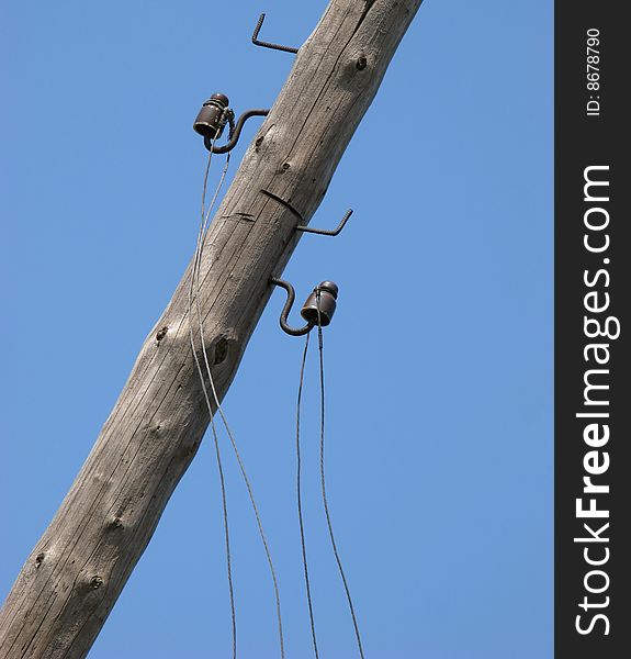 Old collapsing column of an electric main on  background of  blue sky. Old collapsing column of an electric main on  background of  blue sky