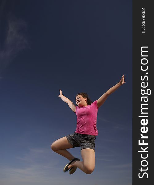 A teen girl leaps into a blue sky, celebrating life. A teen girl leaps into a blue sky, celebrating life.