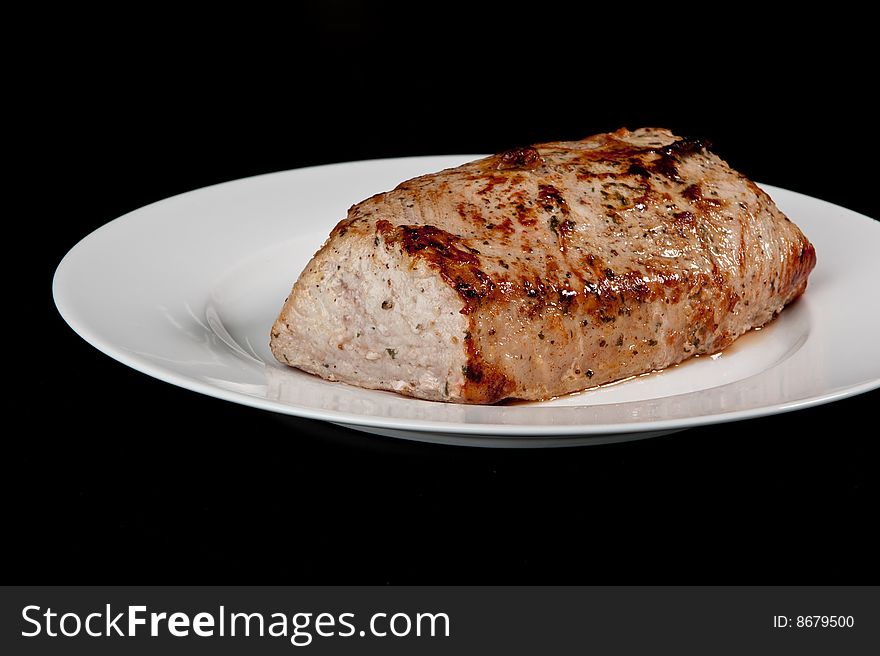 Image of a freshly cooked pork loin on a plate. Image of a freshly cooked pork loin on a plate