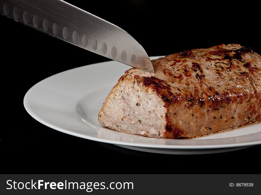 Image of a freshly cooked pork loin on a plate. Image of a freshly cooked pork loin on a plate