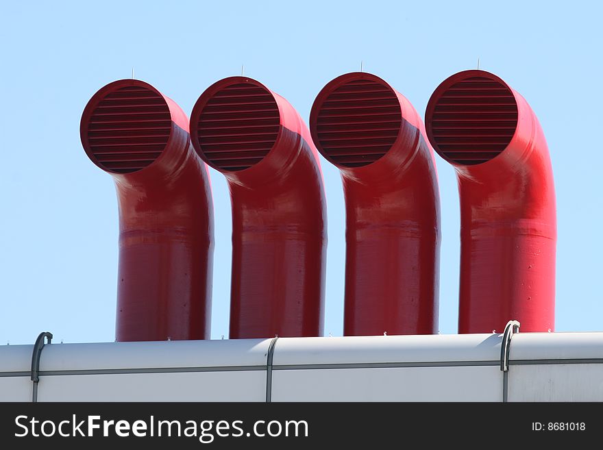 Four Stark Red Metal Factory Pipes on top of Industrial Complex