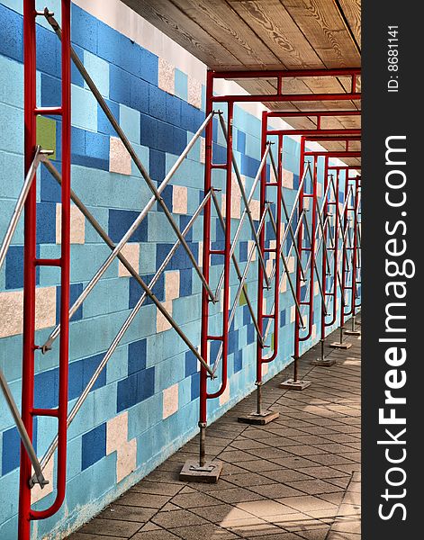 Mosaic Blue and Pink Wall with wooden ceiling, concrete floor, and red iron scaffolding