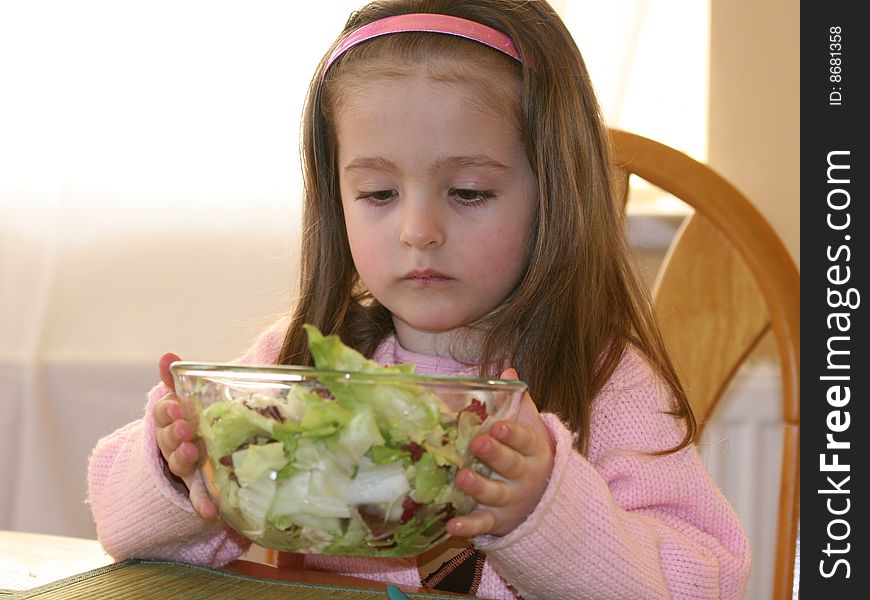 One sitting girl and a cup of vegetables. One sitting girl and a cup of vegetables