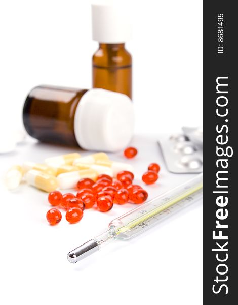 Thermometer and different pills closeup on white background