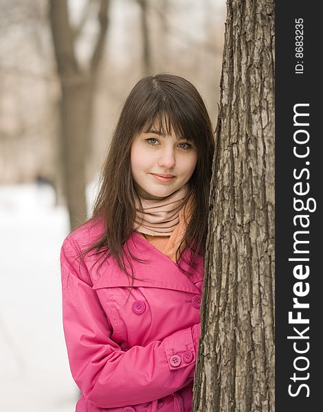 A portrait of smiling young woman in the spring park near big tree. A portrait of smiling young woman in the spring park near big tree