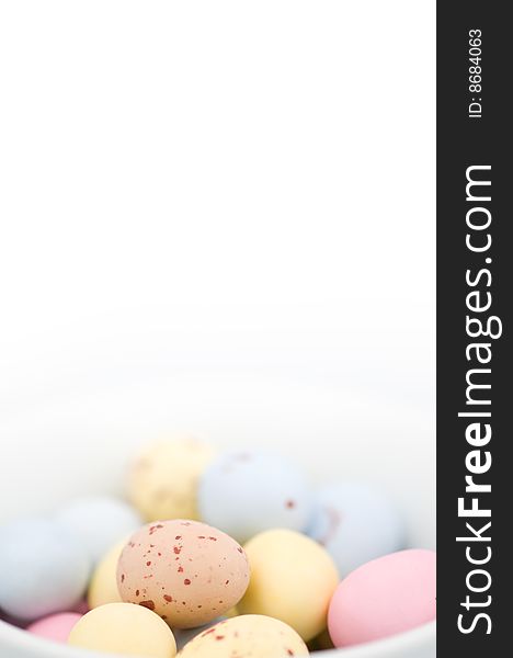 Easter egg chocolate candies on white background and in white bowl. There are some blue, yellow, pink and beige ones. Easter egg chocolate candies on white background and in white bowl. There are some blue, yellow, pink and beige ones...
