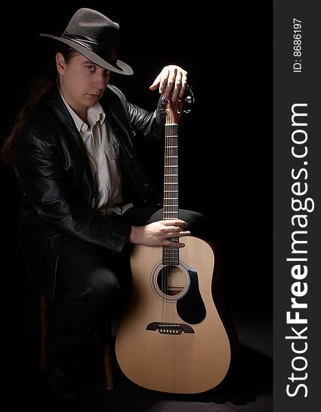 The man in a black hat plays a guitar. The man in a black hat plays a guitar