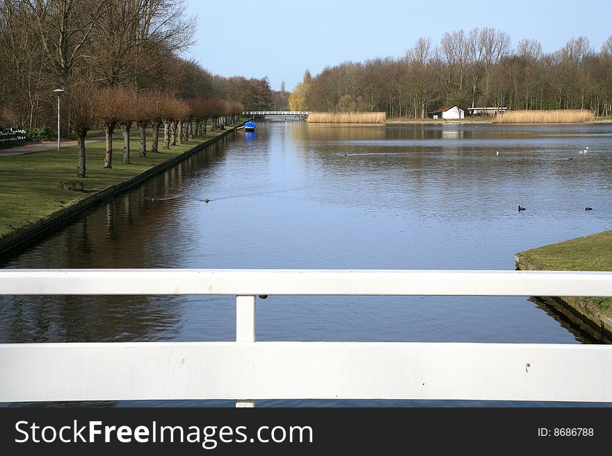 Public garden in The Hague by autumn. Netherlands. Pond and white bridge.