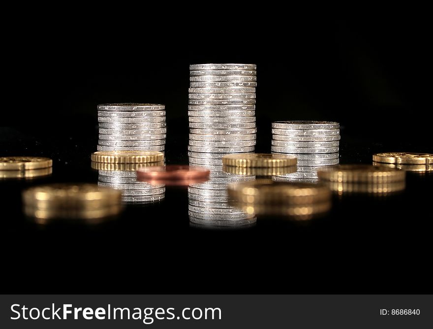 Coins over black background. Reflection in the table.